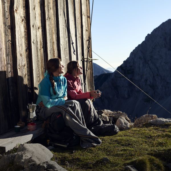 2 Frauen sitzen an einer Hütte am Berg