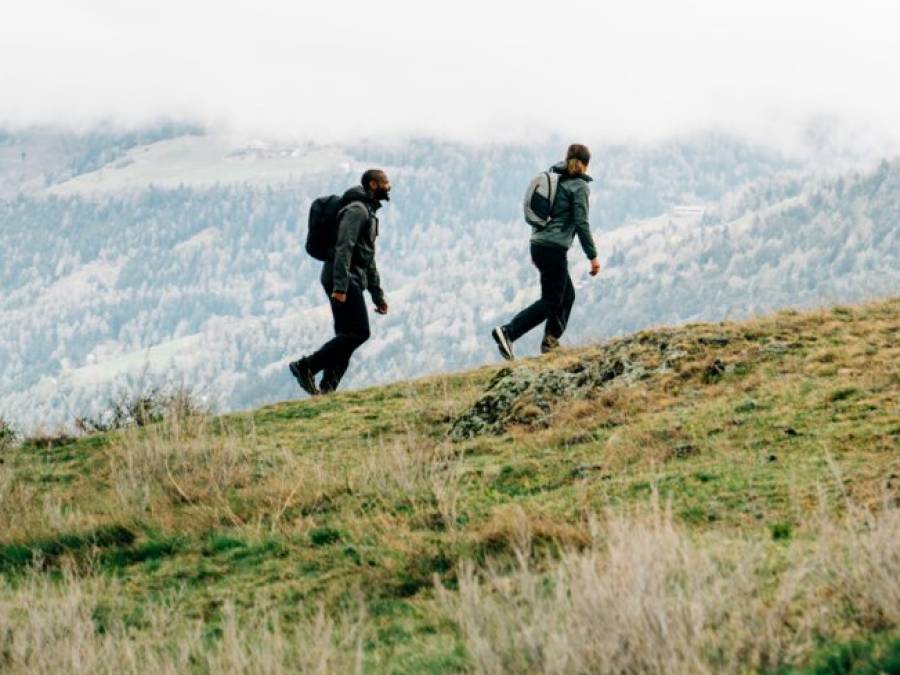 Zwei Personen in hebstlicher Wanderbekleidung wandern über einen Berg