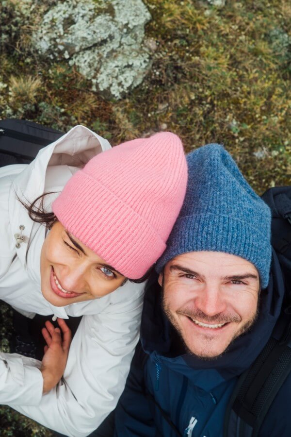 Junger Mann hält eine Sonnenbrille in der Hand und schaut nachdenklich zur Seite vor einer sonnigen Landschaft.
