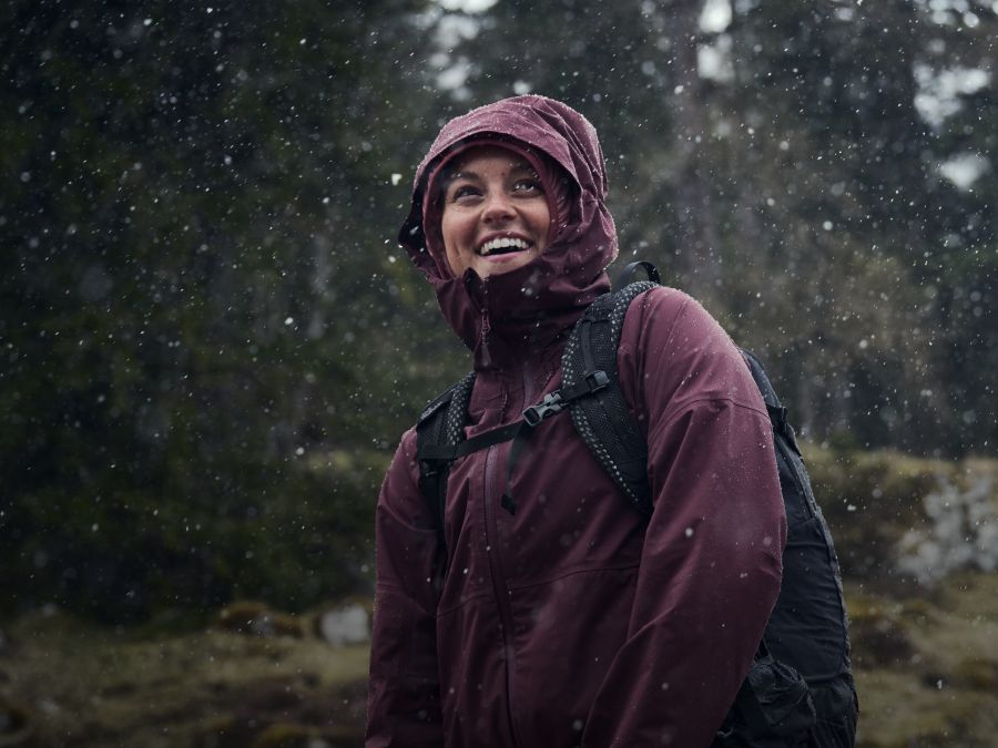 Eine Frau mit Regenjacke bei Regen im Wald