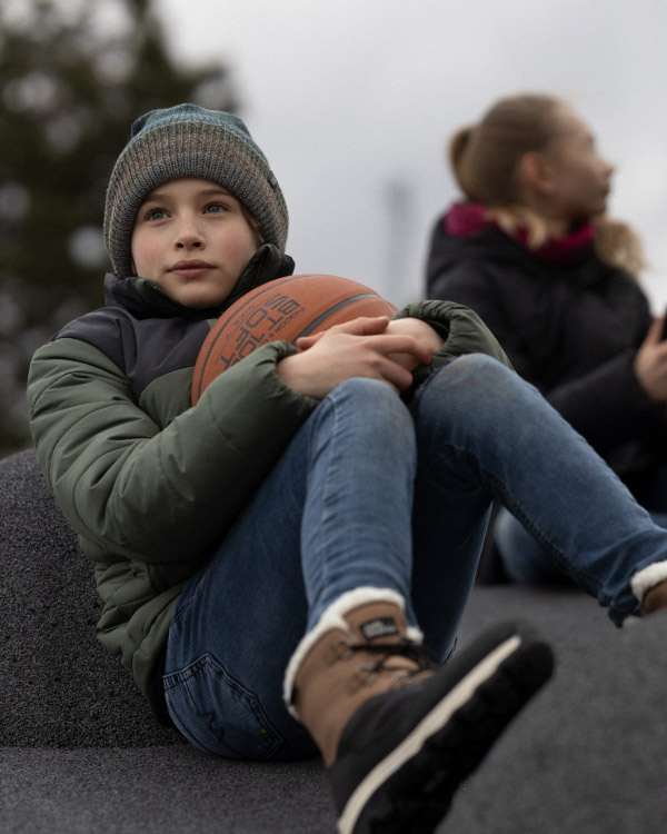 Junge sitzend mit Basketball in den Armen