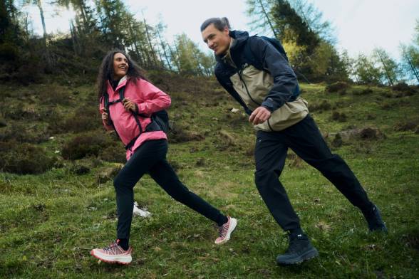 Mann und Frau in sportlicher Wanderbekleidung gehen über eine Lichtung