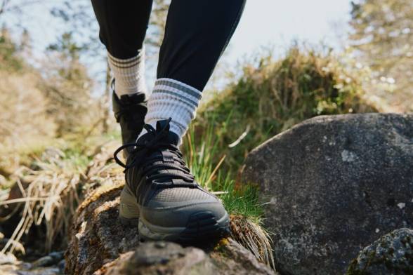 Nahaufnahme einer Person in Wanderschuhen beim Laufen über einen Felsstein