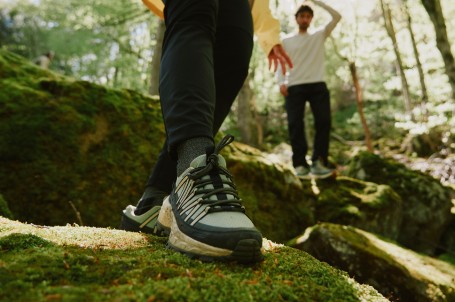 Nahaufnahme von Beinen mit Wanderschuhen auf einem felsigen Weg.